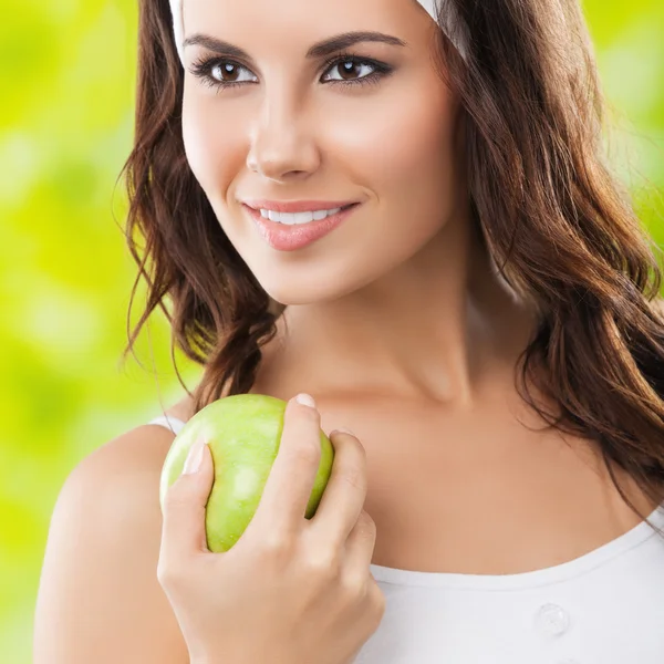 年轻快乐的女人，在用绿色的苹果、 户外运动服 — 图库照片