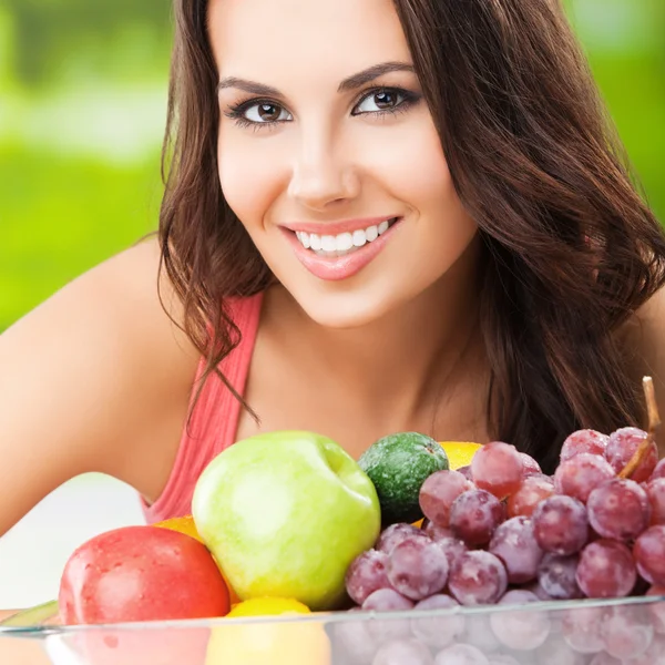 Mulher sorridente com prato de frutas, ao ar livre — Fotografia de Stock