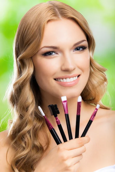 Alegre sorrindo jovem loira mulher com ferramentas de maquiagem, ao ar livre — Fotografia de Stock