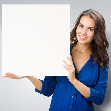Young happy smiling brunette woman showing blank signboard, on g