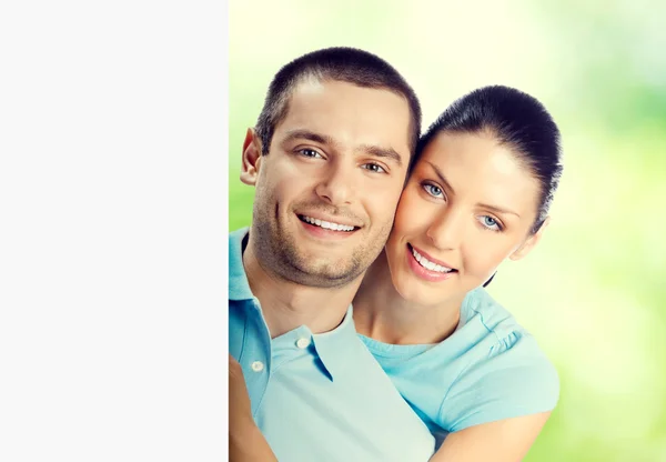 Young lovely couple with blank signboard, outdoor — Stock Photo, Image