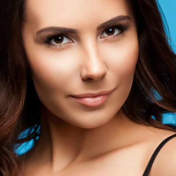 Closeup portret van mooie jonge brunette vrouw, op blauw — Stockfoto