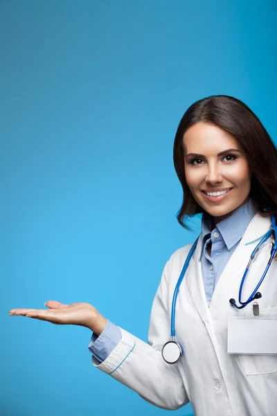 Doctor showing something, on blue — Stock Photo, Image