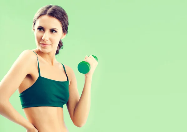 Woman in fitness wear with dumbbell, on green — Stock Photo, Image
