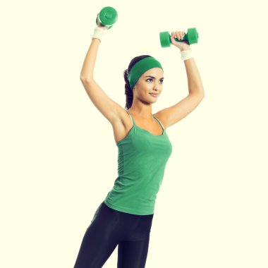 Young brunette woman exercising with dumbbells