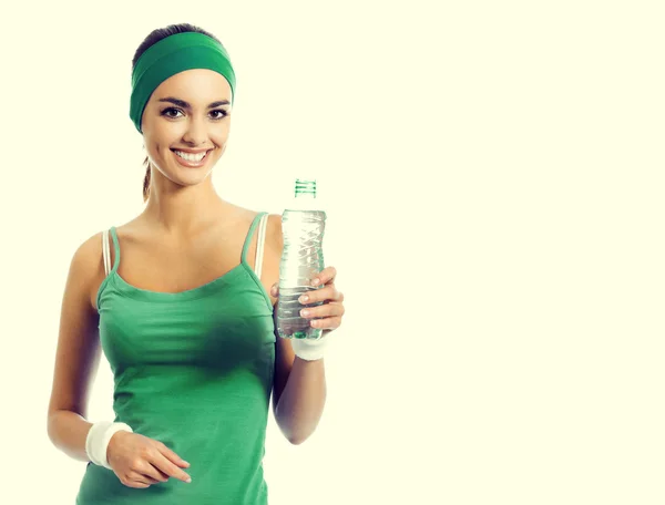 Cheerful young brunette woman in green fitness wear with water — ストック写真