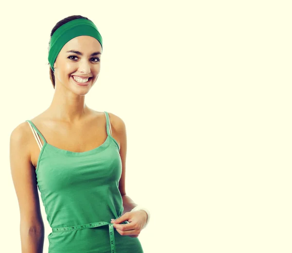 Молода жінка в одязі для фітнесу вимірює талію, з копійкою — стокове фото