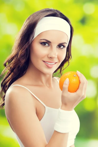 Jeune femme souriante heureuse avec orange, à l'extérieur — Photo