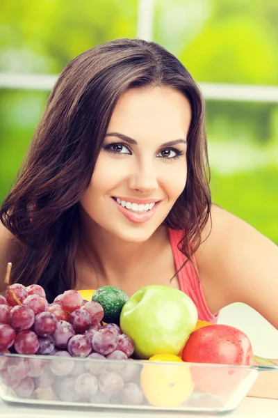 Leende kvinna med platta med frukter, utomhus — Stockfoto