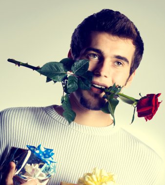 Mutlu bir çekici genç adam hediyeler ve gül, izole whit üzerinde