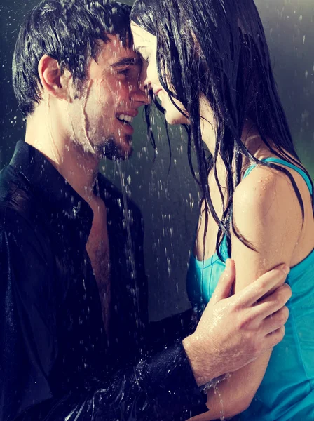 Joven pareja feliz abrazándose bajo una lluvia —  Fotos de Stock