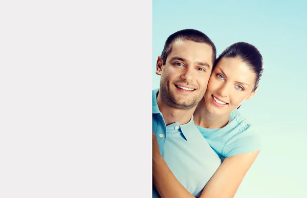 Jovem casal atraente com tabuleta em branco, em azul — Fotografia de Stock