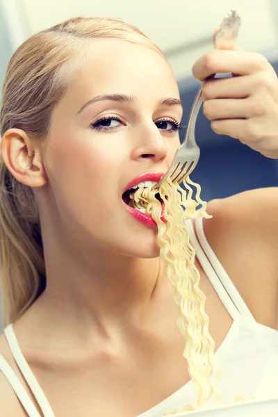 Feliz joven sonriente comiendo espaguetis en el interior —  Fotos de Stock