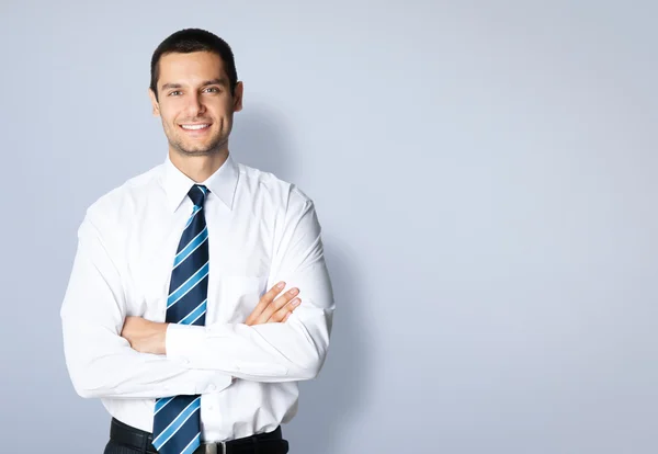 Glücklich lächelnder junger Geschäftsmann gegen grau — Stockfoto