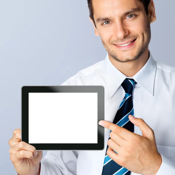 Geschäftsmann zeigt leeren Tablet-PC, auf grau — Stockfoto