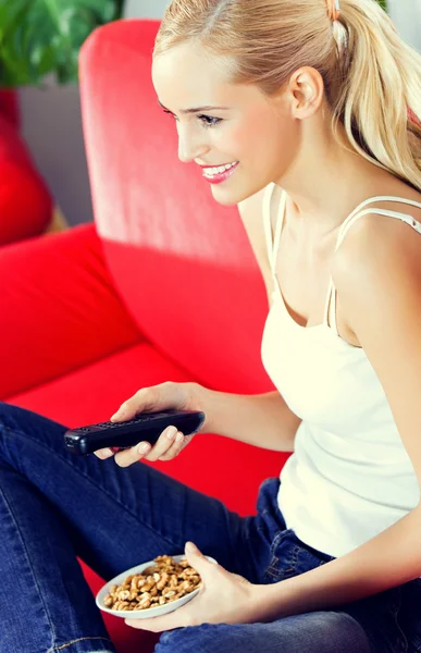 Young happy smiling woman watching TV at home — Stock Photo, Image