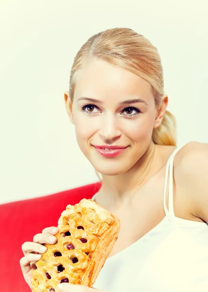 Porträt einer jungen glücklich lächelnden Frau mit Kuchen zu Hause — Stockfoto