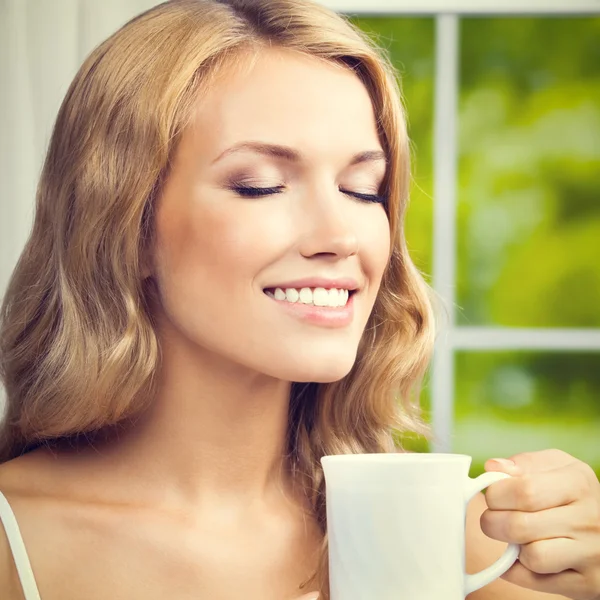 Jeune femme buvant du café ou du thé, à la maison — Photo