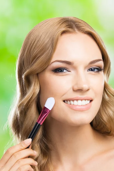 Lachende vrouw met make-up borstel, buiten — Stockfoto