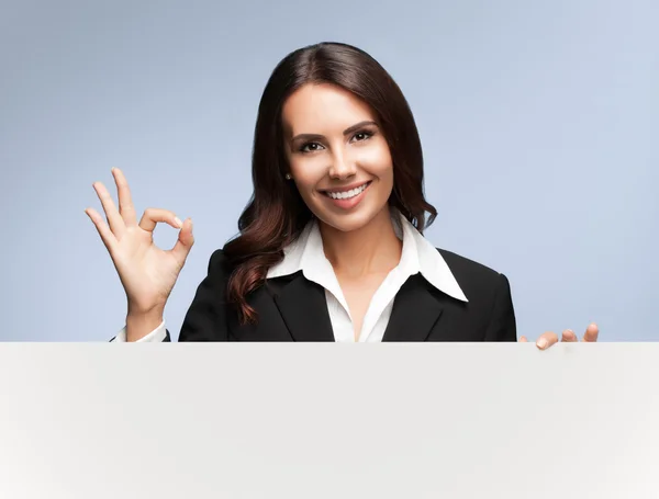 Бізнес-леді, що показує порожню вивіску на сірому — стокове фото
