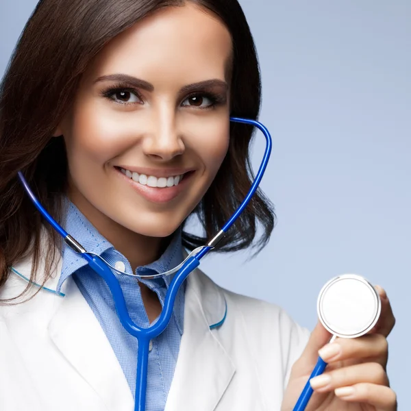 Arzt mit Stethoskop in der Hand, auf grau — Stockfoto