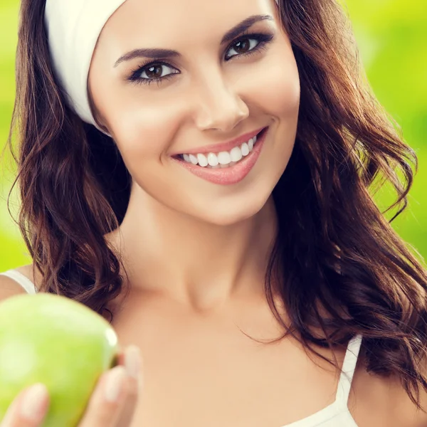 Joven mujer sonriente en ropa deportiva con manzana verde, al aire libre — Foto de Stock