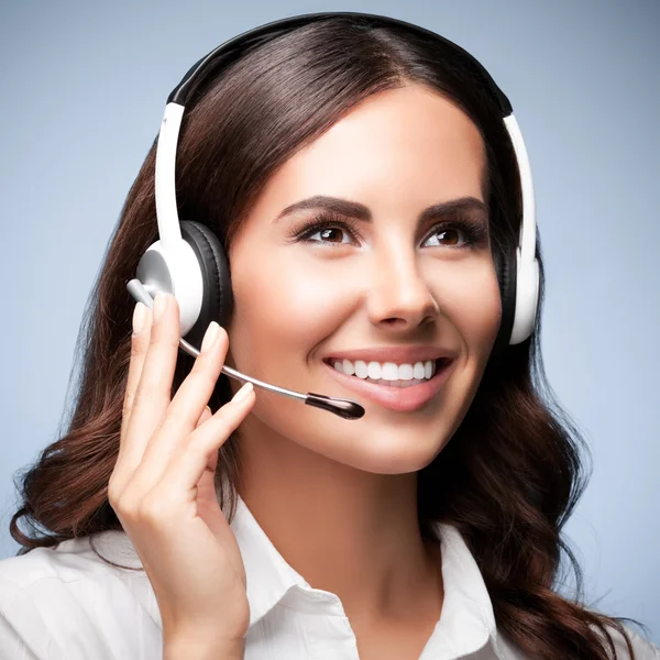 Customer support female phone worker, looking up, against grey — Stock Photo, Image