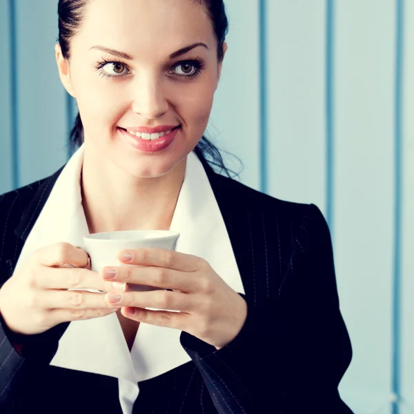 Donna d'affari felice con computer portatile che beve il caffè a ufficio — Foto Stock