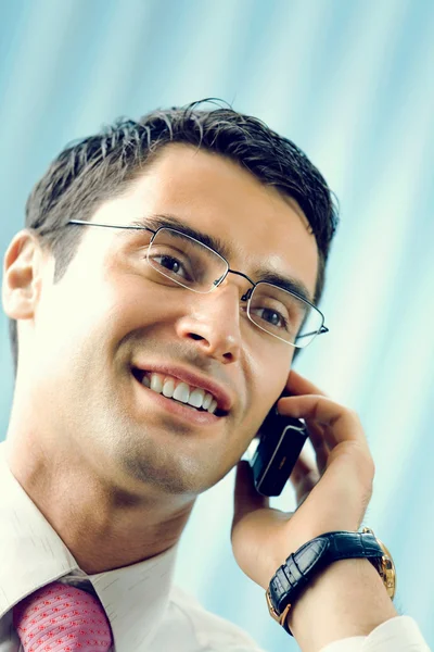 Joven empresario exitoso en el teléfono celular en la oficina — Foto de Stock