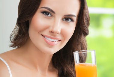 mutlu gülümseyen genç kadın portakal suyu içme
