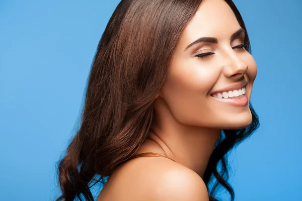 Smiling young woman with closed eyes, on blue — Stock fotografie