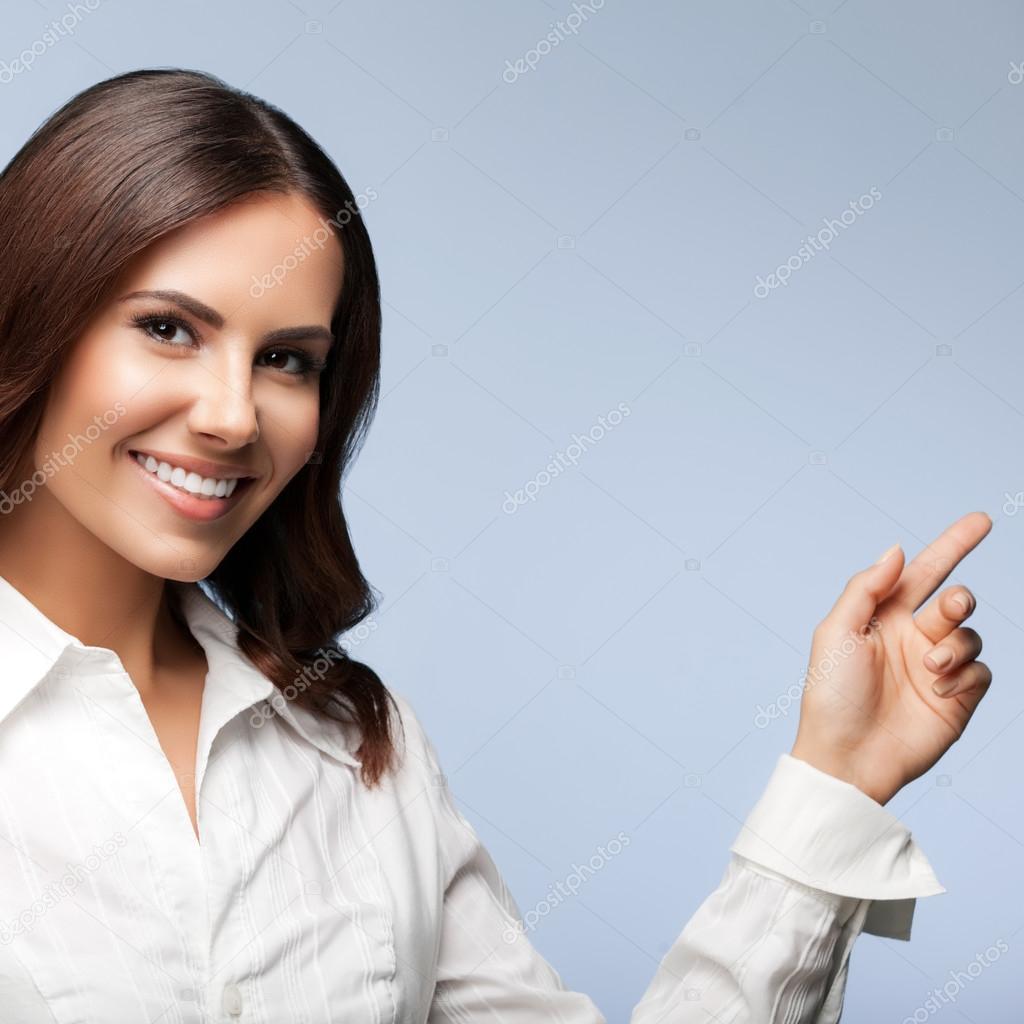 happy smiling young cheerful businesswoman, showing something or blank copyspace area for slogan or text message