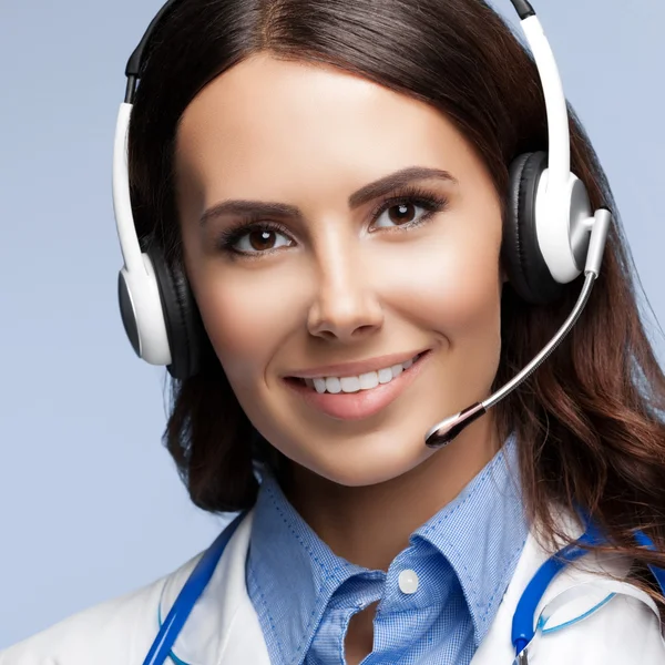 Happy smiling young doctor in headset, on grey — Stock Photo, Image