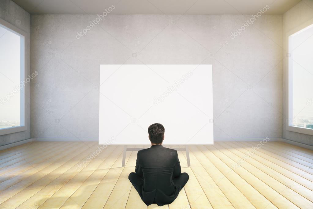 A man sits on the floor and looking at blank poster, mock up, 3d
