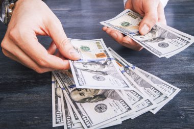 Koyu ahşap yüzeyde Doları banknot sayma eller