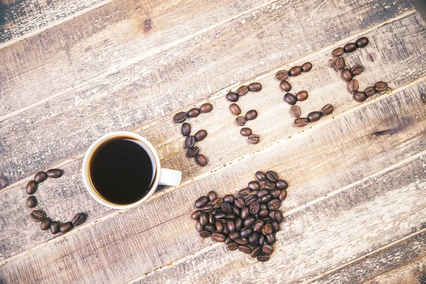 Koffie liefhebber concept met koffiekopje en bonen op houten tafel — Stockfoto