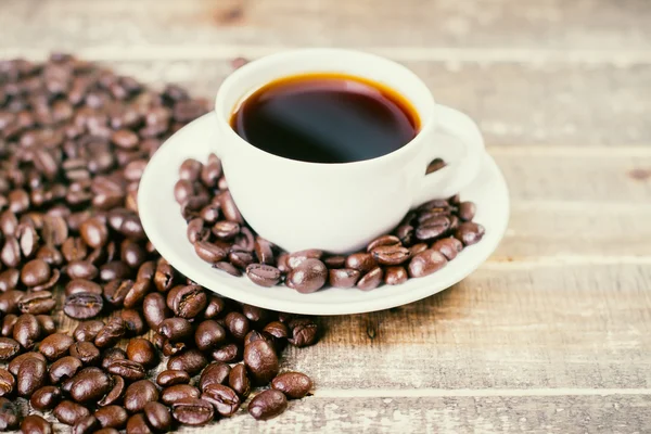 Grãos de café em torno de copo — Fotografia de Stock