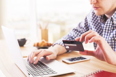 Bilgisayar klavyede yazarak ve bir kredi kartı tutan masada erkek ile online alışveriş ve ödeme kavramı