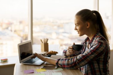 Dizüstü bilgisayarda çalışan genç bir kadın.