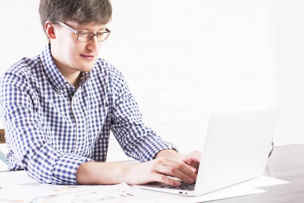 Młody człowiek za pomocą laptopa po stronie — Zdjęcie stockowe