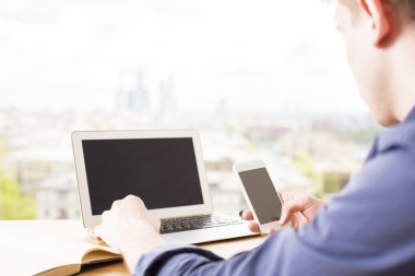 laptop ve telefonu kullanan adam