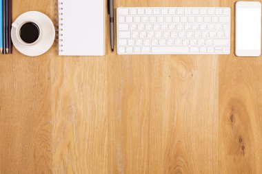 Üstten Görünüm kahve fincanı, spiral not defteri, boş beyaz smartphone, klavye ve diğer öğeleri ile ahşap masaüstü. Yukarı alay