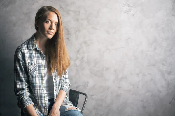 Mädchen sitzt gegen leere Wand — Stockfoto