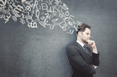 Koyu beton duvara karşı duran çenesi el ile düşünen işadamı