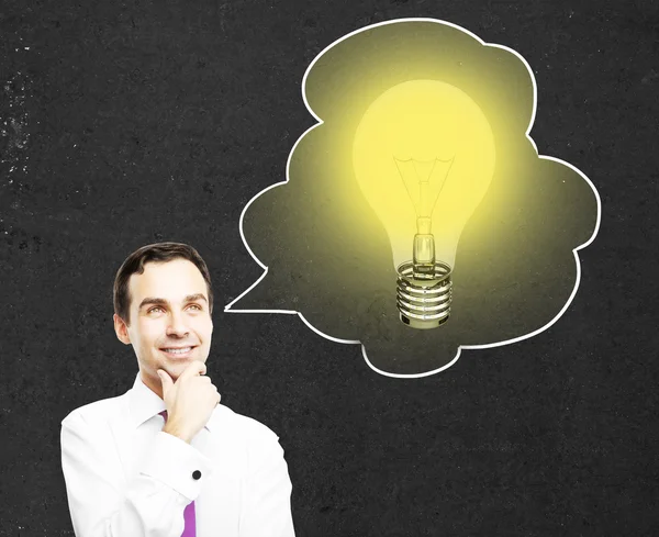 Idea concept with thoughtful businessman on concrete background with lightbulb inside thought cloud — Stock Photo, Image