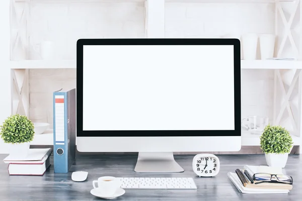 Creative designer desktop with blank white computer monitor, keyboard, stationery items, decorative plants, coffee cup and other items with shelves in the background. Mock up