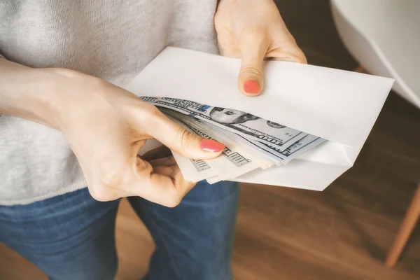 Woman holding envelope with dollars — Stock Photo, Image