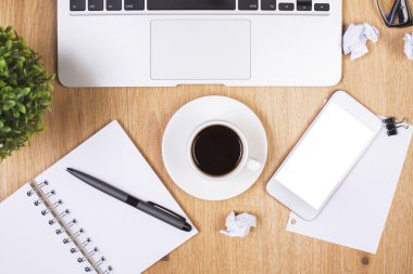 Üstten Görünüm boş beyaz smartphone, kahve fincanı, buruşuk kağıt topları, kırtasiye, laptop klavye ve bitki ile dağınık çalışma alanı'nın. Yukarı alay