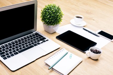 Boş dizüstü bilgisayar, dekoratif bitki, spiral not defteri, kahve fincanları, tablet, akıllı telefon ve diğer öğeleri ile yaratıcı tasarımcı çalışma alanı closeup. Alay etmek