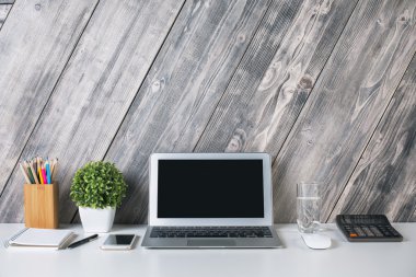Yaratıcı tasarımcı masaüstü boş dizüstü, smartphone, hesap makinesi, bitki, kırtasiye, su cam ve diğer öğeleri ile önden görünümü. Yukarı alay